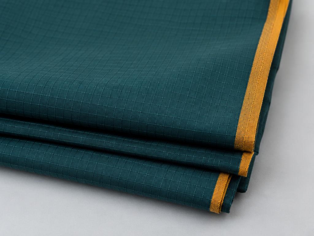 Folded teal ripstop fabric with an ochre edge